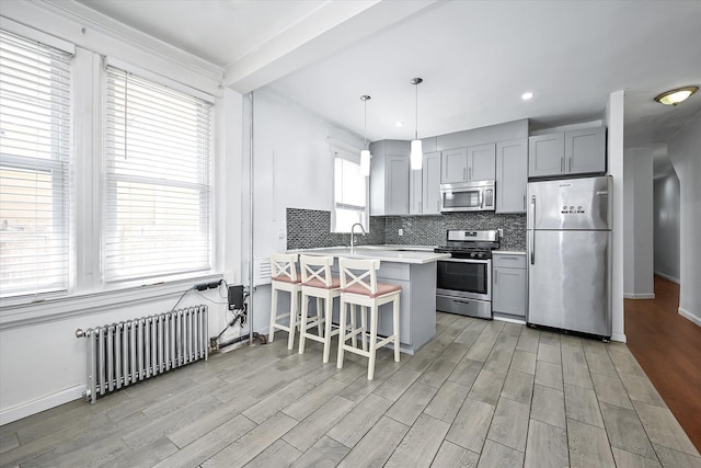 27-34 Mcintosh St, East Elmhurst, NY 11369 - kitchen with stainless steel appliances, radiator, gray cabinetry, backsplash, and light countertops