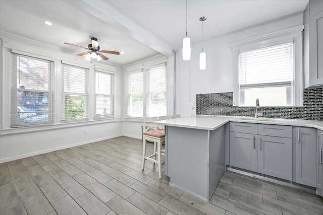 27-34 Mcintosh St, East Elmhurst, NY 11369 - kitchen featuring gray cabinets, a sink, a ceiling fan, backsplash, and a kitchen bar