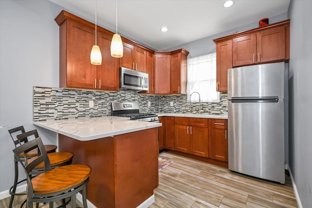 27-34 Mcintosh St, East Elmhurst, NY 11369 - kitchen with stainless steel appliances, a peninsula, brown cabinetry, decorative light fixtures, and a kitchen breakfast bar