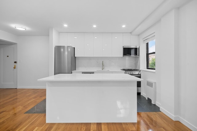 25-10 31st Ave Unit 2M, Astoria, NY 11106 - kitchen featuring stainless steel appliances, radiator, modern cabinets, white cabinetry, and a sink