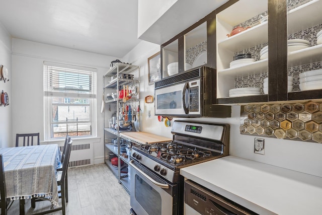 35-05 72nd St Unit 6F, Jackson Heights, NY 11372 - kitchen featuring appliances with stainless steel finishes, radiator, open shelves, and light wood-style flooring