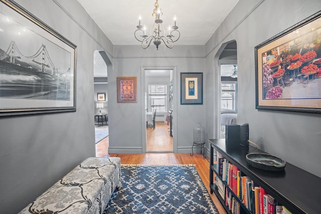 35-05 72nd St Unit 6F, Jackson Heights, NY 11372 - hallway featuring arched walkways, light wood-style floors, a chandelier, and baseboards
