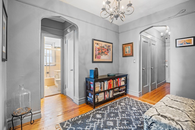 35-05 72nd St Unit 6F, Jackson Heights, NY 11372 - bedroom with a chandelier, arched walkways, wood finished floors, and baseboards