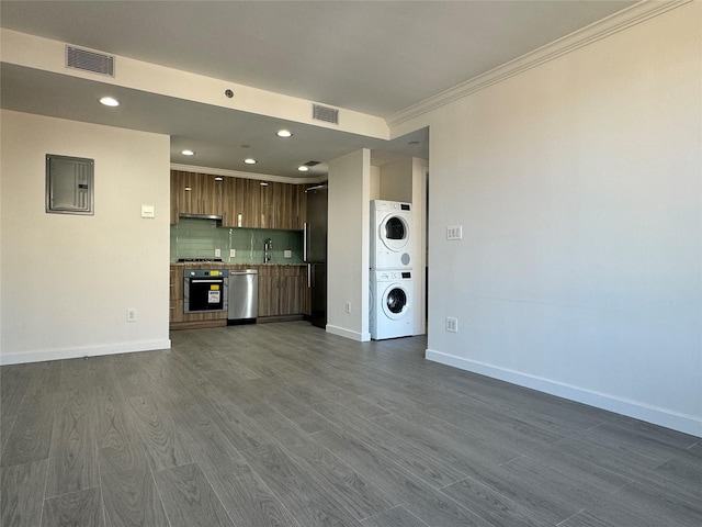 132-27 41st Rd Unit 7E, Flushing, NY 11355 - unfurnished living room with stacked washing machine and dryer, crown molding, baseboards, electric panel, and recessed lighting