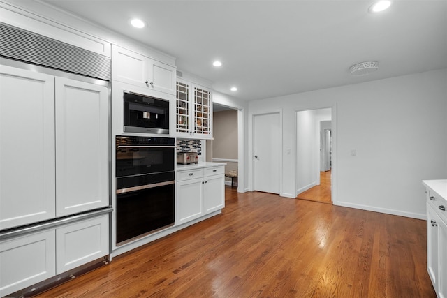 6 Ogden Rd, Scarsdale, NY 10583 - kitchen featuring paneled built in fridge, glass insert cabinets, white cabinets, light wood-type flooring, and baseboards
