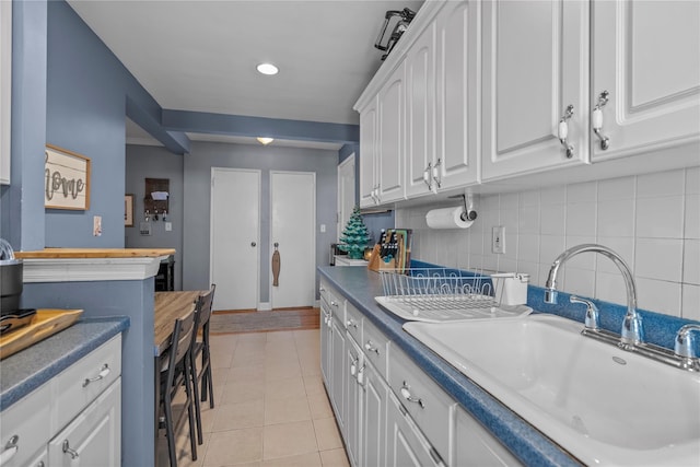 60 Locust Ave Unit 610, New Rochelle, NY 10801 - kitchen with a sink, white cabinetry, decorative backsplash, light tile patterned floors, and baseboards