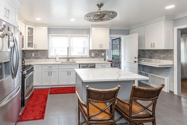 426 N High St, Mount Vernon, NY 10552 - kitchen with appliances with stainless steel finishes, a breakfast bar, white cabinetry, tasteful backsplash, and crown molding