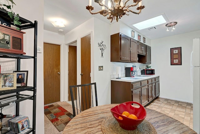 192 Ventry Ct Unit A, Ridge, NY 11961 - kitchen featuring a skylight, a chandelier, light countertops, dark brown cabinets, and decorative backsplash