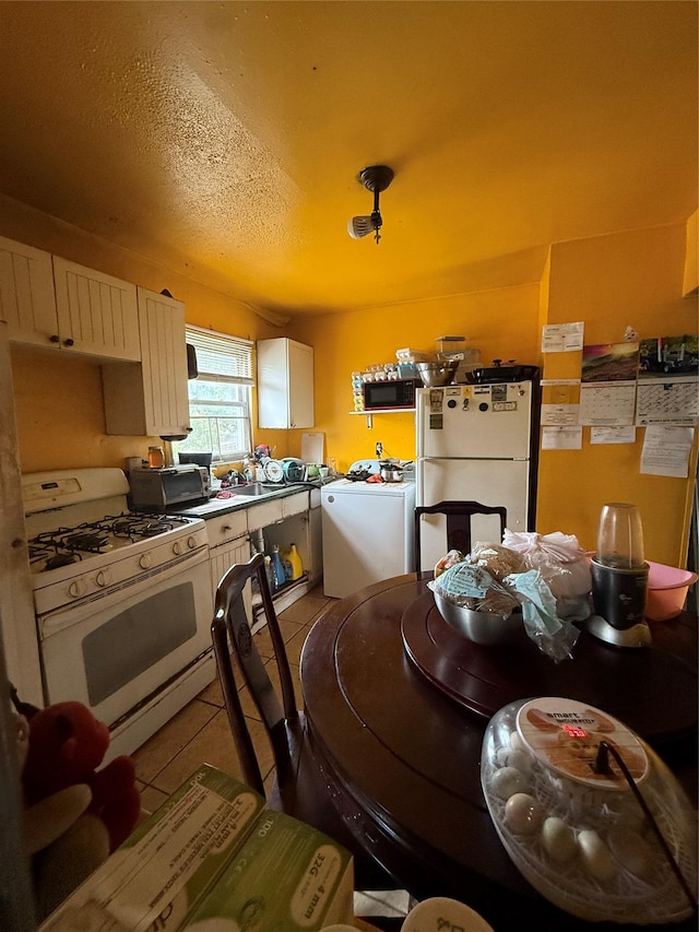 328 Brentwood Pkwy, Brentwood, NY 11717 - kitchen featuring white appliances, washer / dryer, light tile patterned flooring, a sink, and white cabinets