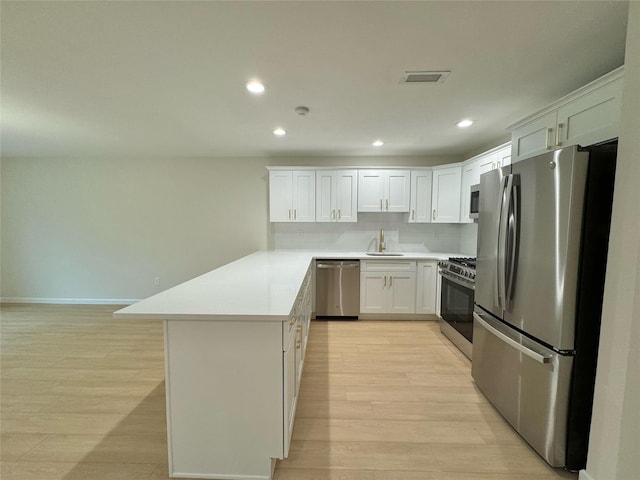 19 Erin Ln, East Setauket, NY 11733 - kitchen with stainless steel appliances, a peninsula, a sink, recessed lighting, and light wood-style flooring