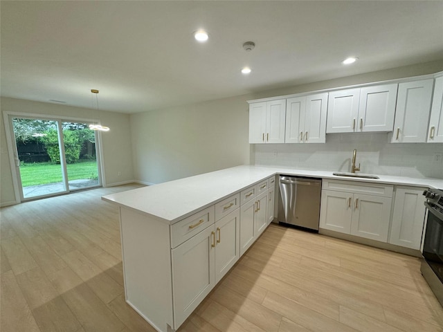 19 Erin Ln, East Setauket, NY 11733 - kitchen featuring appliances with stainless steel finishes, a sink, light wood-style floors, a peninsula, and light countertops