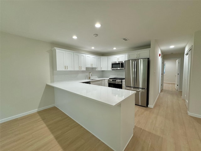19 Erin Ln, East Setauket, NY 11733 - kitchen with stainless steel appliances, a sink, a peninsula, light countertops, and light wood-style flooring