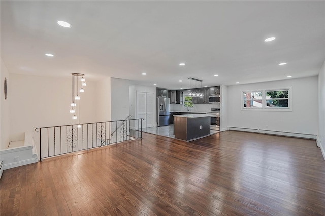 71 Cinnamon St, Central Islip, NY 11722 - unfurnished living room with baseboard heating, dark wood-type flooring, recessed lighting, and baseboards