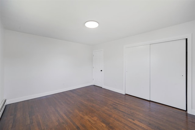 71 Cinnamon St, Central Islip, NY 11722 - unfurnished bedroom with dark wood finished floors, baseboards, a closet, and baseboard heating