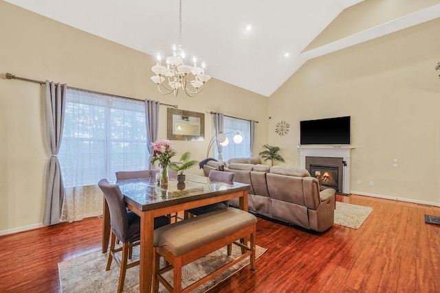 15 Arielle Ct, Hauppauge, NY 11749 - dining area featuring high vaulted ceiling, a chandelier, wood finished floors, a glass covered fireplace, and baseboards