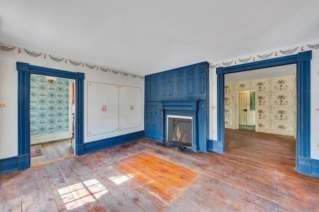 201 E Broadway Prt, Jefferson, NY 11777 - unfurnished living room featuring wood-type flooring, a fireplace, wallpapered walls, and baseboards