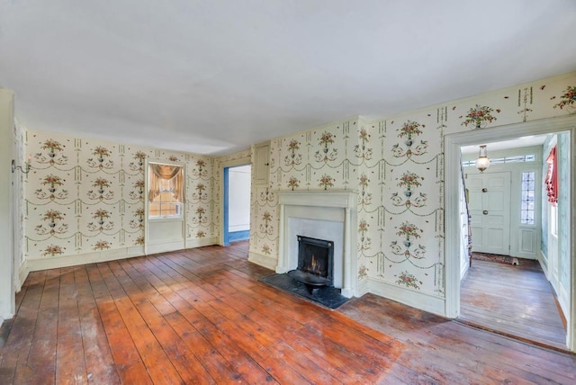 201 E Broadway Prt, Jefferson, NY 11777 - unfurnished living room featuring wallpapered walls, hardwood / wood-style floors, a fireplace with flush hearth, and baseboards