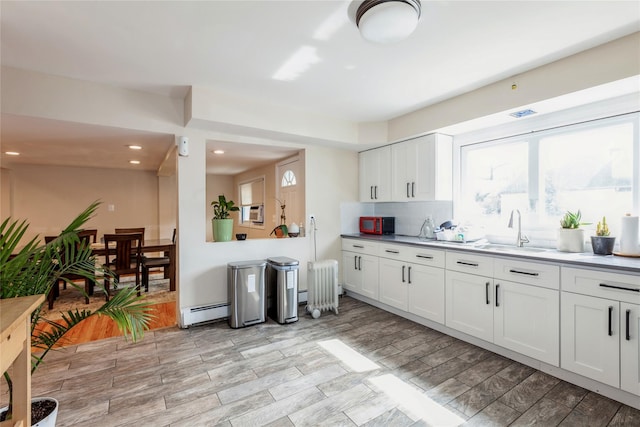 55 Nassau Ave, Glen Cove, NY 11542 - kitchen featuring a sink, radiator, a baseboard radiator, decorative backsplash, and white cabinetry