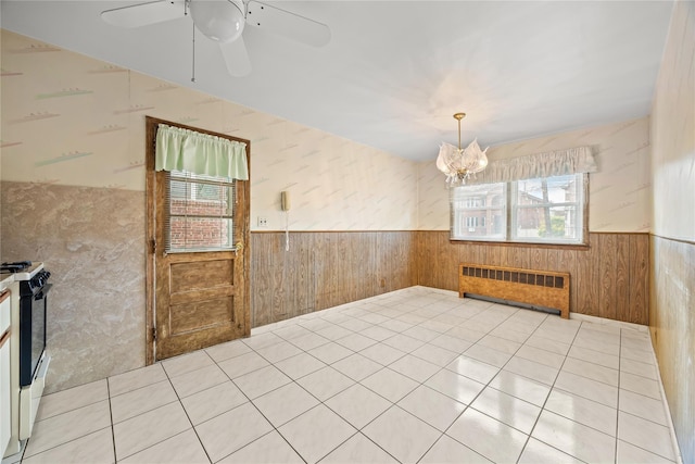 150-44 23rd Ave, Whitestone, NY 11357 - unfurnished dining area featuring a wainscoted wall, radiator, wood walls, ceiling fan, and a chandelier