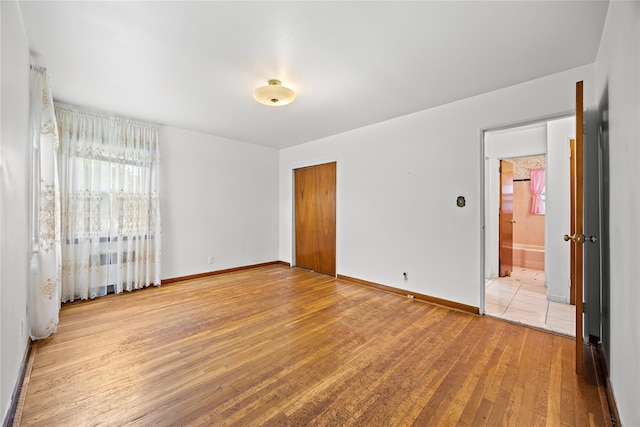 150-44 23rd Ave, Whitestone, NY 11357 - unfurnished bedroom with light wood-type flooring, a closet, baseboards, and ensuite bathroom