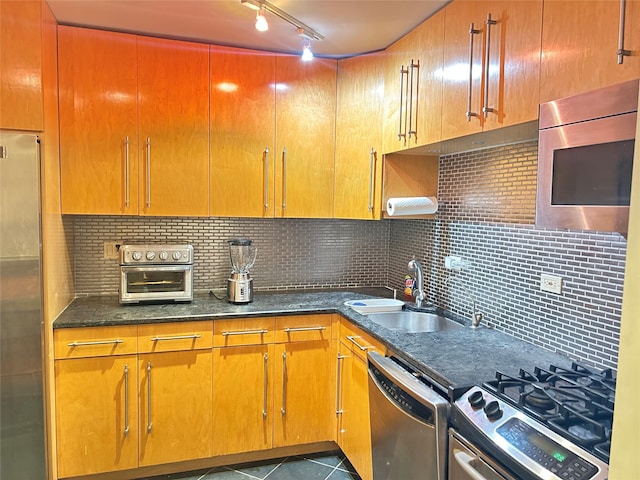 ONE Bay Club Dr Unit 18S, Bayside, NY 11360 - kitchen with appliances with stainless steel finishes, a sink, dark tile patterned flooring, track lighting, and decorative backsplash