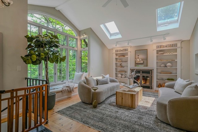 10 Maple Ave, Setauket, NY 11733 - living room with a skylight, hardwood / wood-style floors, rail lighting, lofted ceiling, and a fireplace with flush hearth