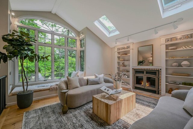 10 Maple Ave, Setauket, NY 11733 - living area with a skylight, track lighting, vaulted ceiling, wood finished floors, and built in shelves