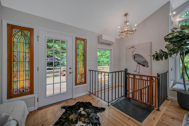 10 Maple Ave, Setauket, NY 11733 - entryway featuring a wall unit AC, a chandelier, vaulted ceiling, wood-type flooring, and baseboards