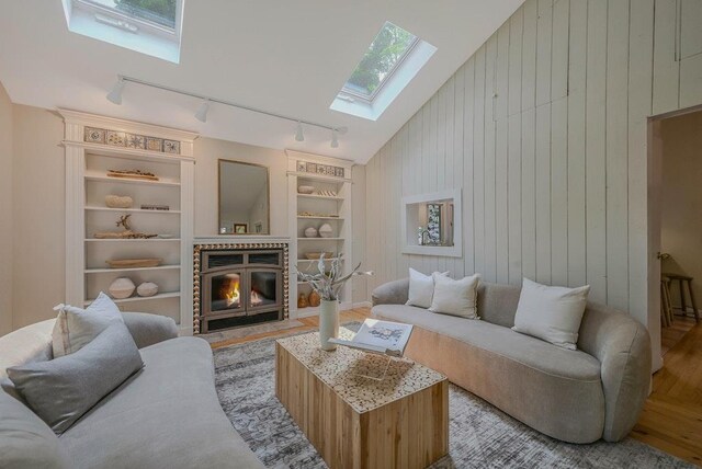 10 Maple Ave, Setauket, NY 11733 - living room featuring rail lighting, a skylight, built in shelves, wood finished floors, and wooden walls