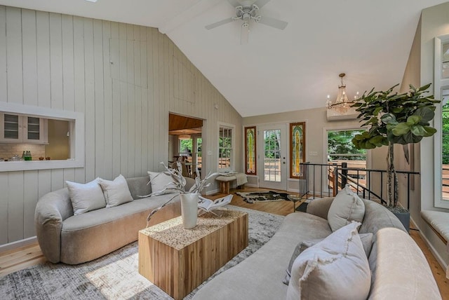 10 Maple Ave, Setauket, NY 11733 - living room featuring wood finished floors, wooden walls, high vaulted ceiling, ceiling fan, and a chandelier