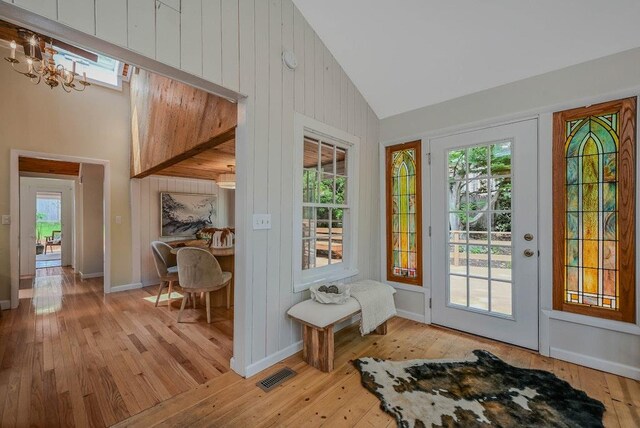 10 Maple Ave, Setauket, NY 11733 - doorway featuring light wood finished floors, high vaulted ceiling, a chandelier, and baseboards