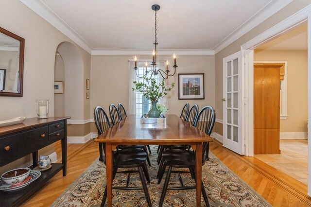 12 5th Pl, Garden City, NY 11530 - dining room with a chandelier, arched walkways, light wood-style flooring, ornamental molding, and baseboards