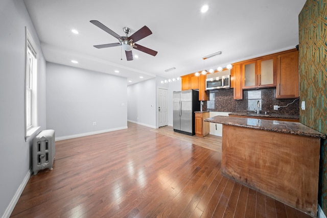 114-23 Sutter Ave, South Ozone Park, NY 11420 - kitchen featuring stainless steel appliances, ceiling fan, brown cabinetry, backsplash, and light wood-style flooring