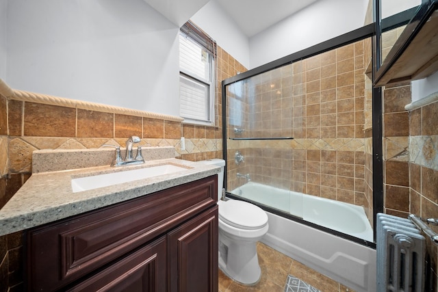 114-23 Sutter Ave, South Ozone Park, NY 11420 - full bathroom featuring radiator heating unit, toilet, shower / bath combination with glass door, tile walls, and vanity