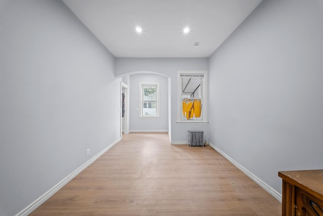 114-23 Sutter Ave, South Ozone Park, NY 11420 - unfurnished living room with radiator, arched walkways, light wood-style floors, recessed lighting, and baseboards