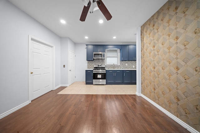 114-23 Sutter Ave, South Ozone Park, NY 11420 - kitchen with stainless steel appliances, blue cabinets, ceiling fan, baseboards, and light wood-type flooring