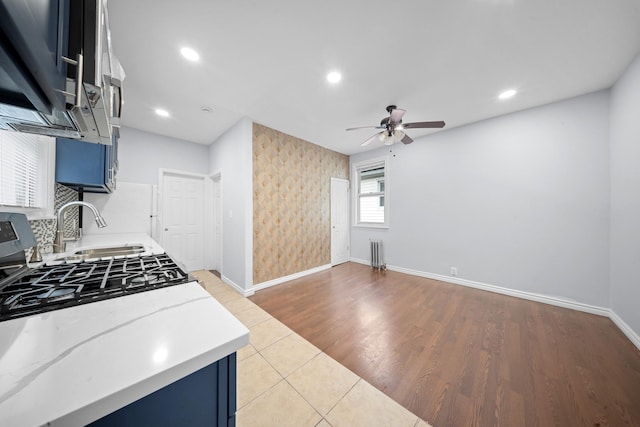 114-23 Sutter Ave, South Ozone Park, NY 11420 - kitchen with radiator heating unit, blue cabinetry, a ceiling fan, light countertops, and recessed lighting