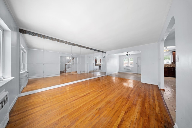 1549 E 57th St, Brooklyn, NY 11234 - unfurnished living room featuring arched walkways, stairway, wood-type flooring, baseboards, and ceiling fan
