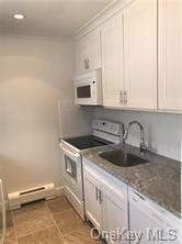 49 Tanager Rd Unit 4905, Monroe, NY 10950 - kitchen with white appliances, a baseboard heating unit, a sink, and white cabinetry