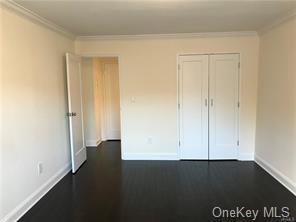 49 Tanager Rd Unit 4905, Monroe, NY 10950 - unfurnished bedroom with baseboards, crown molding, dark wood finished floors, and a closet