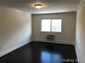 49 Tanager Rd Unit 4905, Monroe, NY 10950 - empty room with dark wood finished floors, baseboard heating, ornamental molding, baseboards, and an AC wall unit