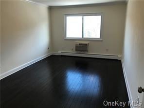 49 Tanager Rd Unit 4905, Monroe, NY 10950 - spare room with dark wood-style flooring, baseboards, a wall mounted air conditioner, and baseboard heating