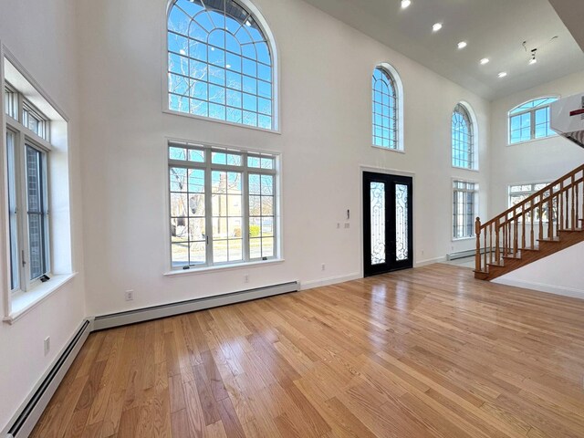 36-46 205th St, Bayside, NY 11361 - entryway featuring wood finished floors, a baseboard radiator, stairway, a high ceiling, and baseboards