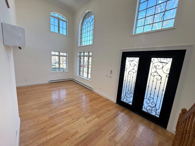 36-46 205th St, Bayside, NY 11361 - foyer featuring light wood-style flooring, healthy amount of natural light, baseboards, a high ceiling, and a wall mounted air conditioner