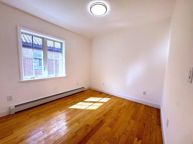 36-46 205th St, Bayside, NY 11361 - spare room with a baseboard heating unit, light wood-style floors, and baseboards