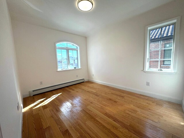 36-46 205th St, Bayside, NY 11361 - spare room with a baseboard heating unit, light wood-type flooring, and baseboards
