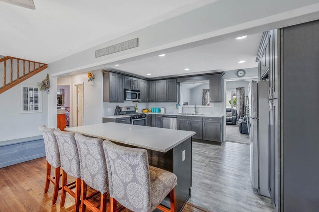 379 Columbus Ave, West Babylon, NY 11704 - kitchen featuring appliances with stainless steel finishes, a breakfast bar area, a sink, light wood finished floors, and recessed lighting