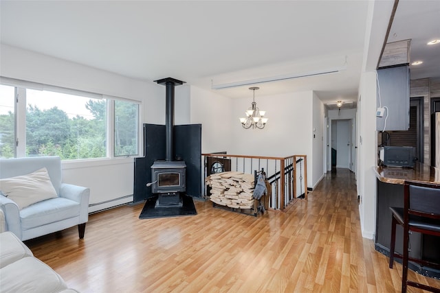 112 Middle Island Blvd, Middle Island, NY 11953 - living room with a baseboard heating unit, a wood stove, light wood-style floors, and a chandelier