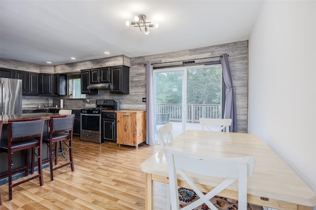 112 Middle Island Blvd, Middle Island, NY 11953 - kitchen with stainless steel appliances, under cabinet range hood, light wood-style floors, dark cabinets, and decorative backsplash