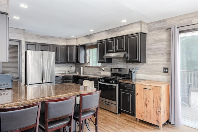 112 Middle Island Blvd, Middle Island, NY 11953 - kitchen with stainless steel appliances, under cabinet range hood, light wood-style flooring, dark cabinets, and tasteful backsplash